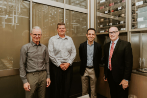 Four men standing next to each other in a room, preparing for ASRS 2022.