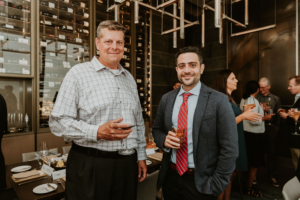 Two men standing next to each other in a restaurant at ASRS 2022.