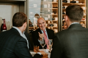 A group of men sitting at a table in a restaurant, discussing their plans for ASRS 2022.