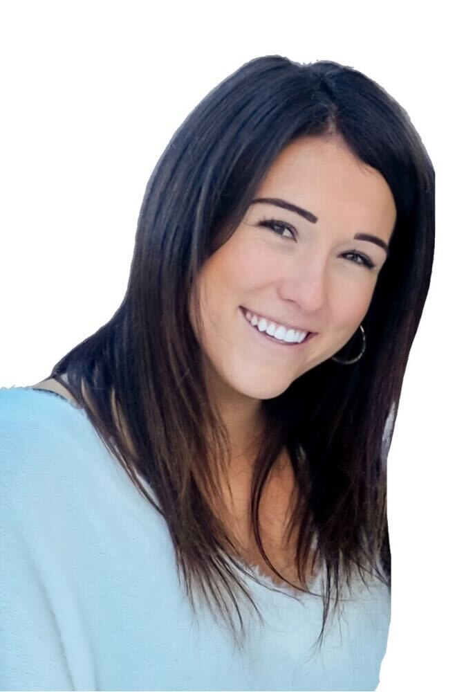 A woman with long hair smiling for the camera, while holding a vial.