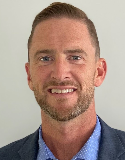 A man in a suit and blue shirt is smiling during an oncology conference.