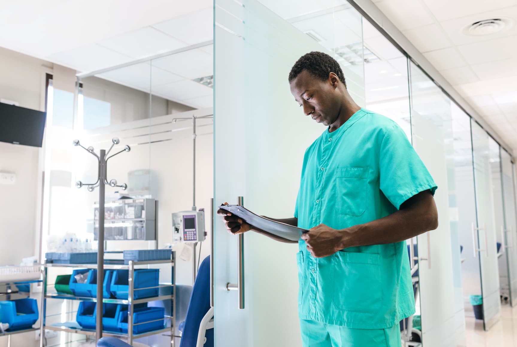 A man in scrubs is holding a clipboard in an oncology trial.