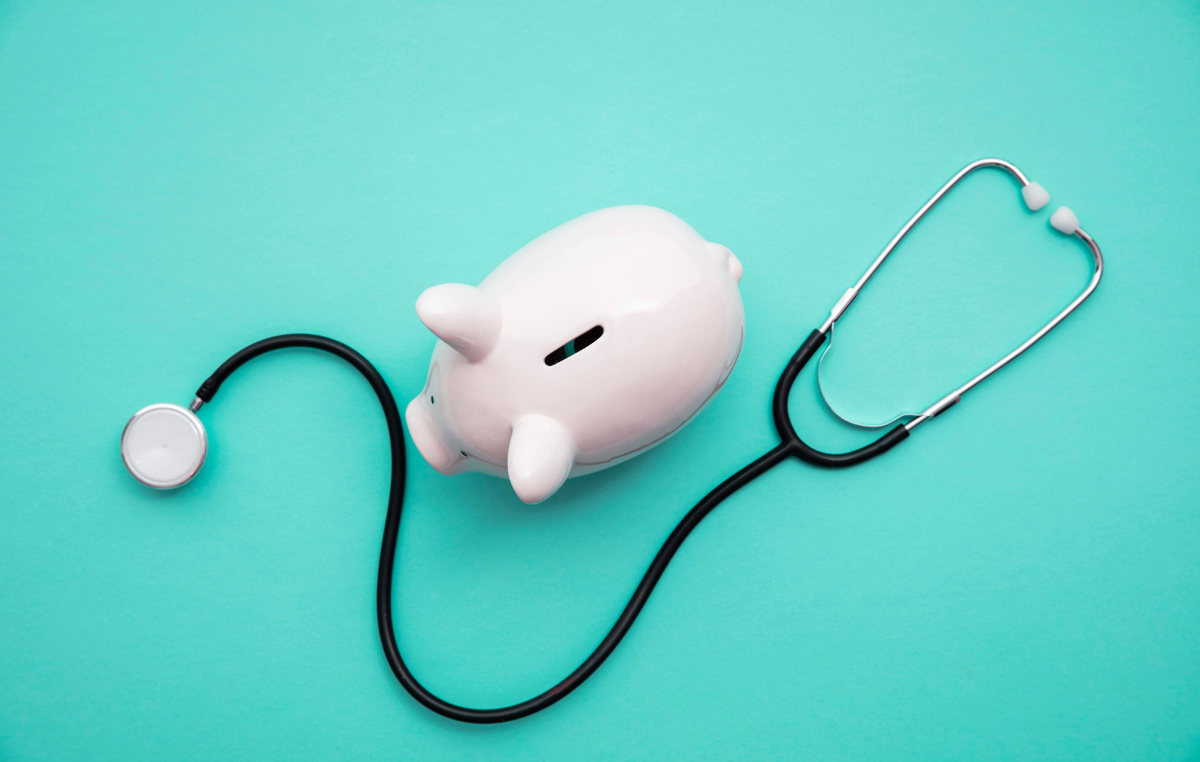 Piggy bank and stethoscope on turquoise background, symbolizing financial change.