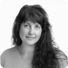 A black and white photo of a woman with curly hair holding a vial.