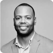 A black and white photo of a man smiling at the East Coast Summit.