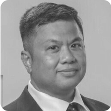 A black and white photo of a man in a suit posing with a vial.