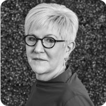 A vintage black and white photo featuring a woman wearing glasses.