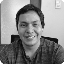 A black and white photo of a man smiling, holding a vial.