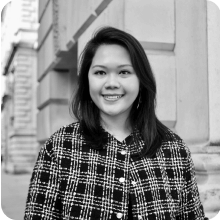 A woman in a plaid jacket poses for a black and white photo.