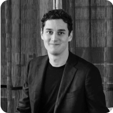 A black and white photo of a man in a suit attending a Summit.