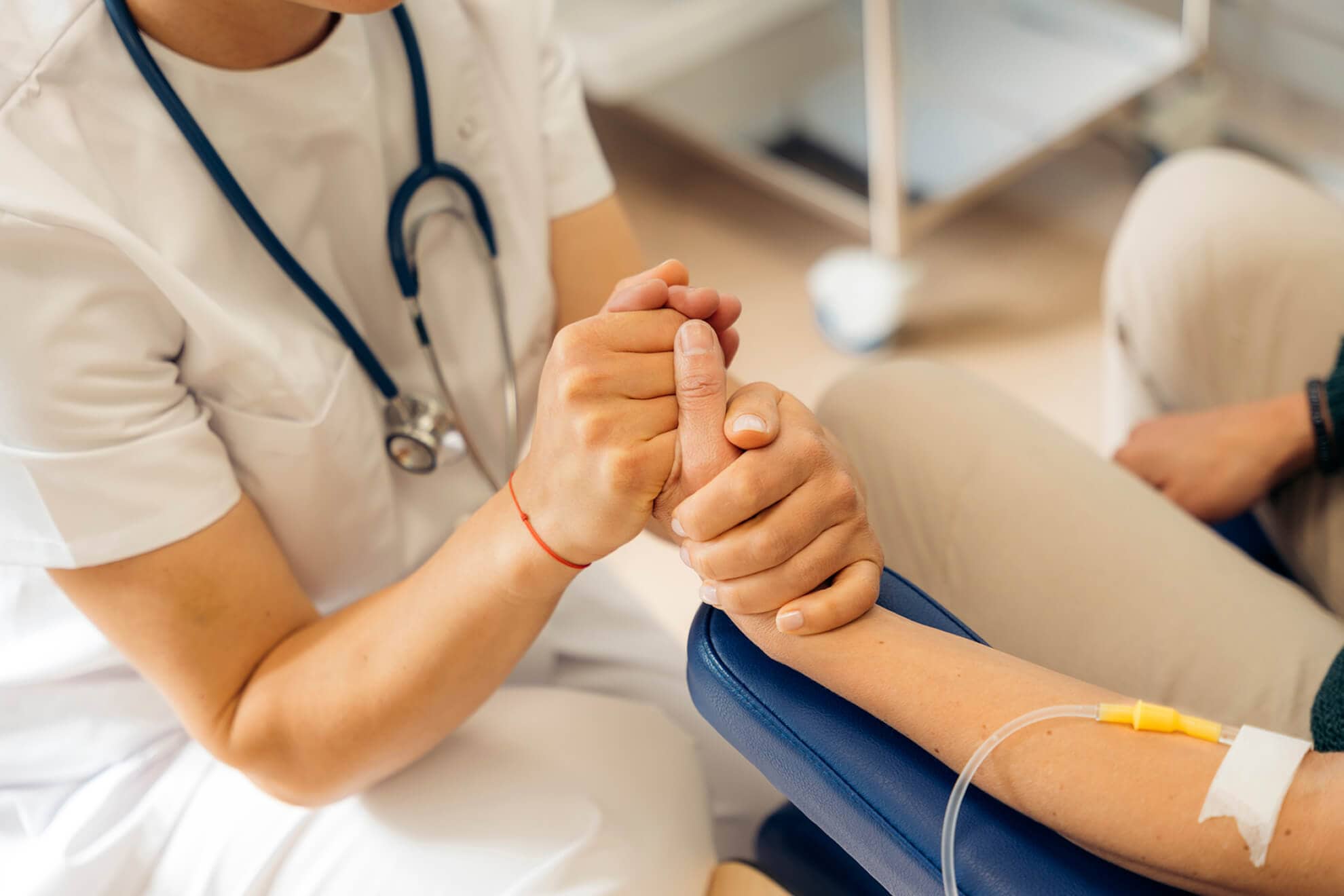 A nurse is holding a patient's hand during their battle with esophageal cancer.