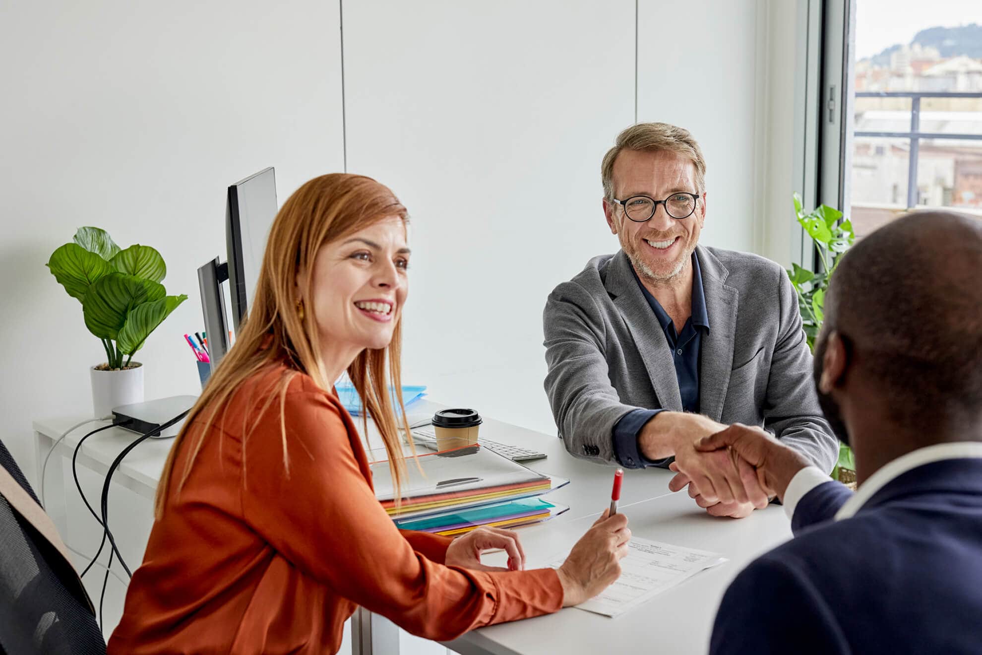 Two CROs shaking hands at a desk in an office.