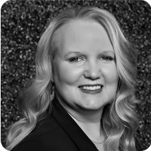 A black and white photo of a woman with a vial smiling.