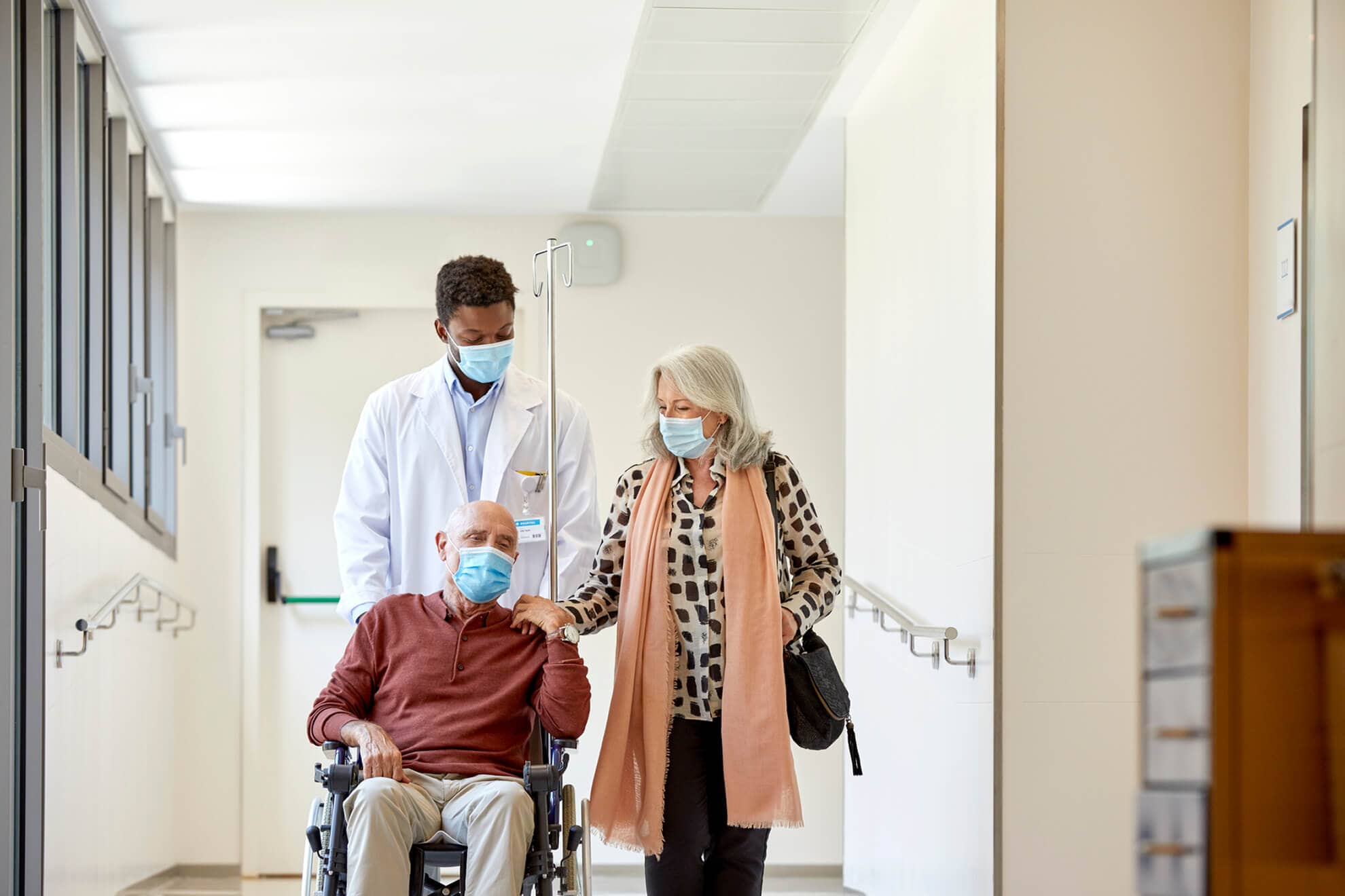 A compassionate male nurse assists a senior man in a wheelchair.