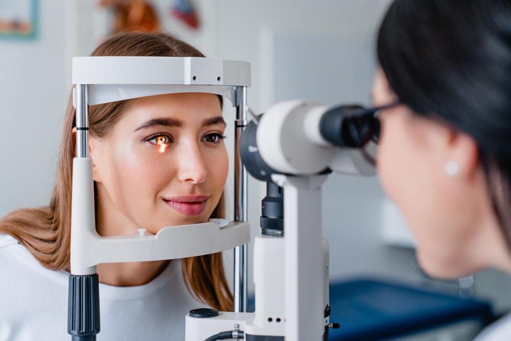 Eye doctor with female patient during an examination in a modern clinic, using advanced equipment for precise diagnostics.